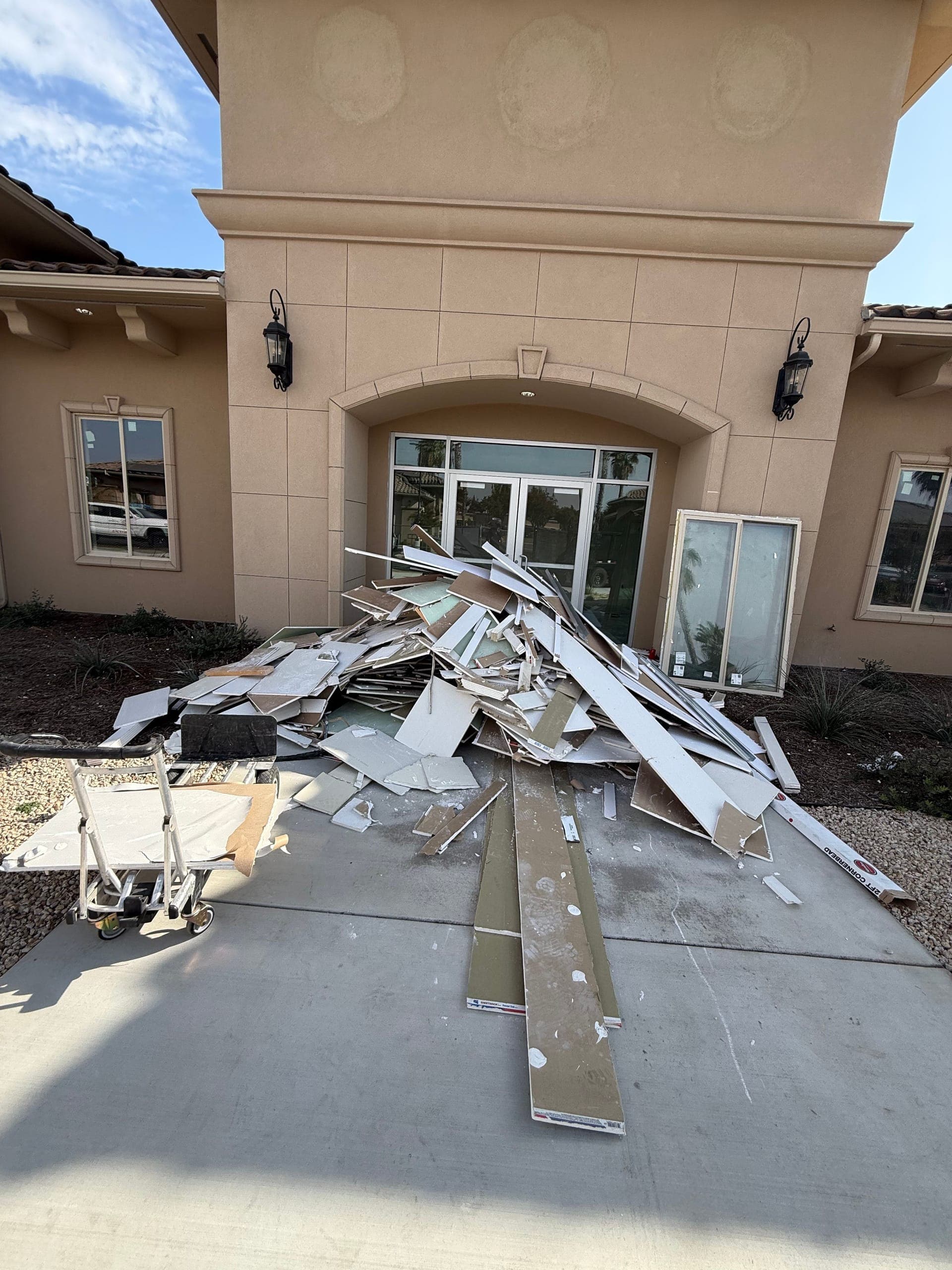 Pile of drywall and construction debris at a new commercial building entrance in Clovis