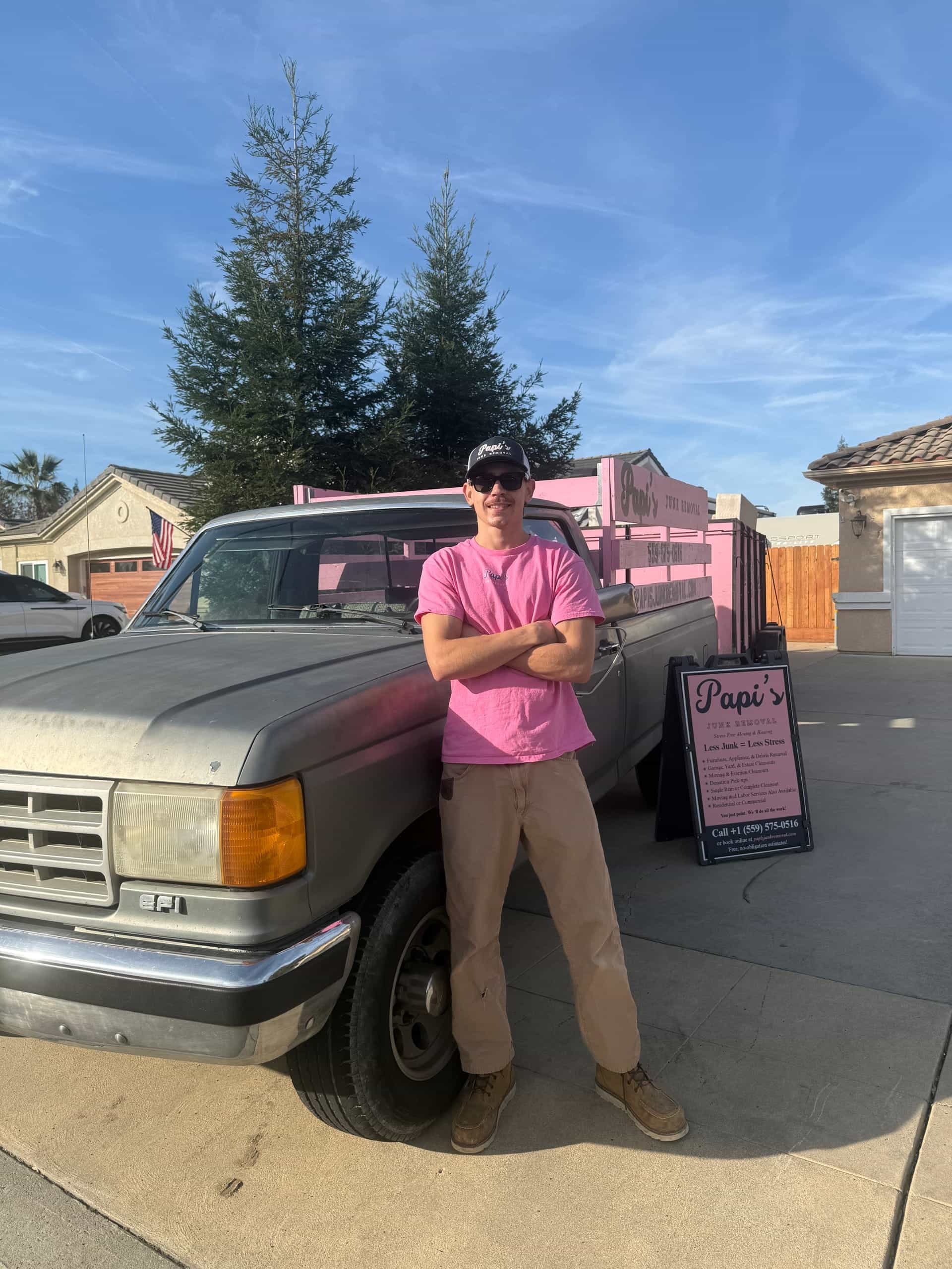 Papi's crew member leaning on the Ford pickup with the pink rack and Papi's yard sign