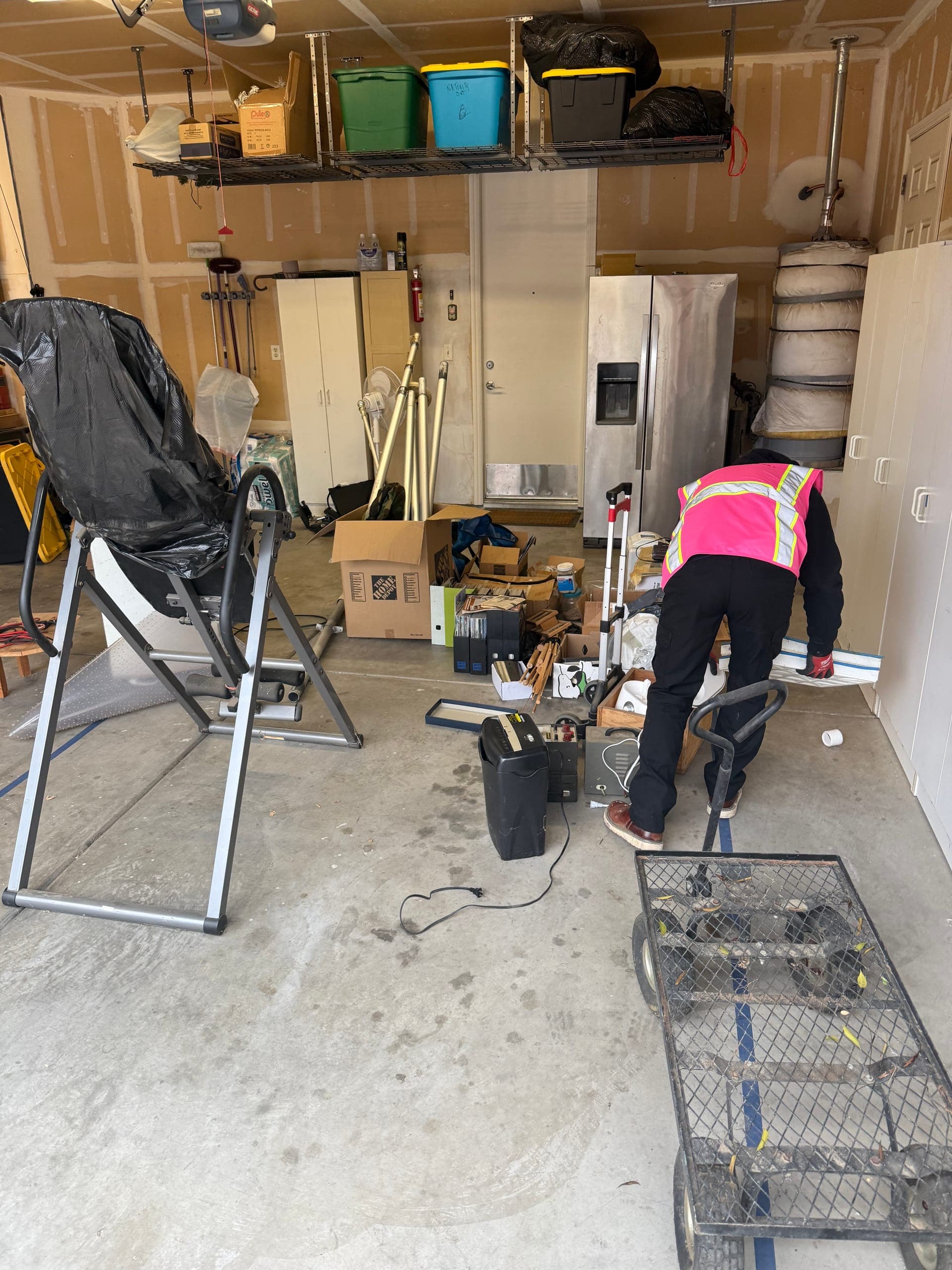 Papi's crew member in a pink safety vest clearing a garage