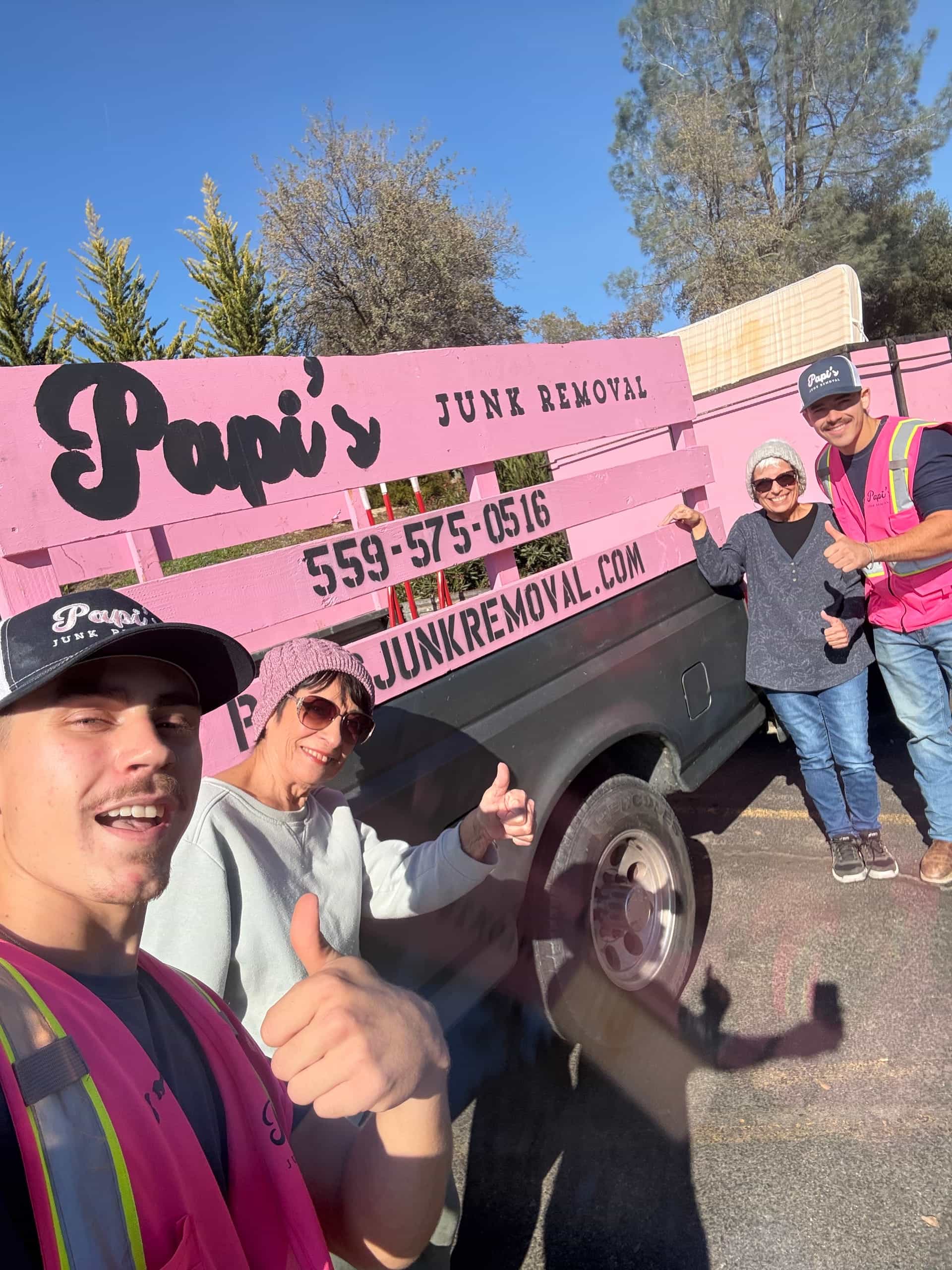 Papi's crew member taking a selfie with happy customers in front of the pink-rack truck