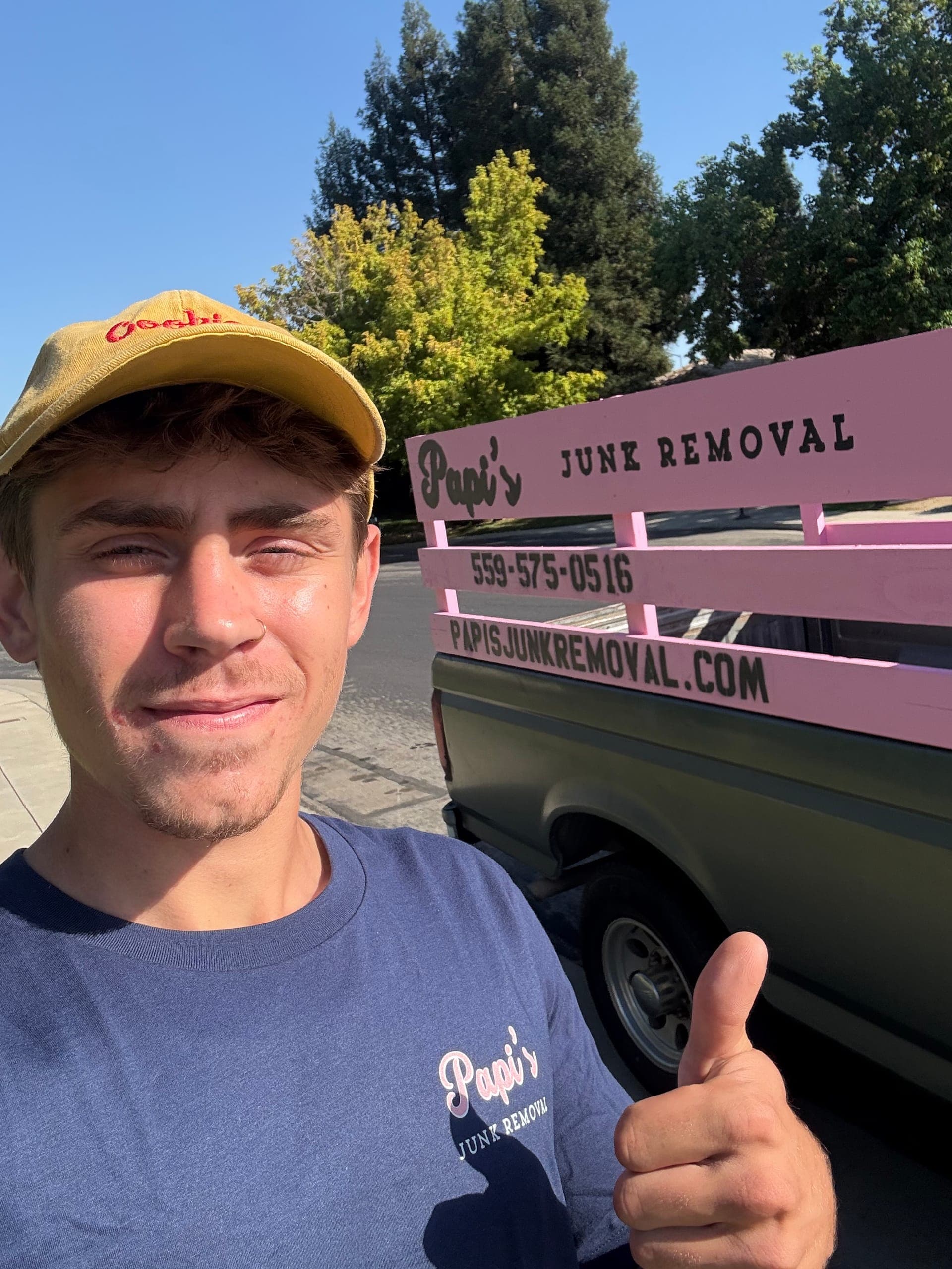Papi's crew member in a yellow Papi's cap giving a thumbs-up next to the pink-rack truck