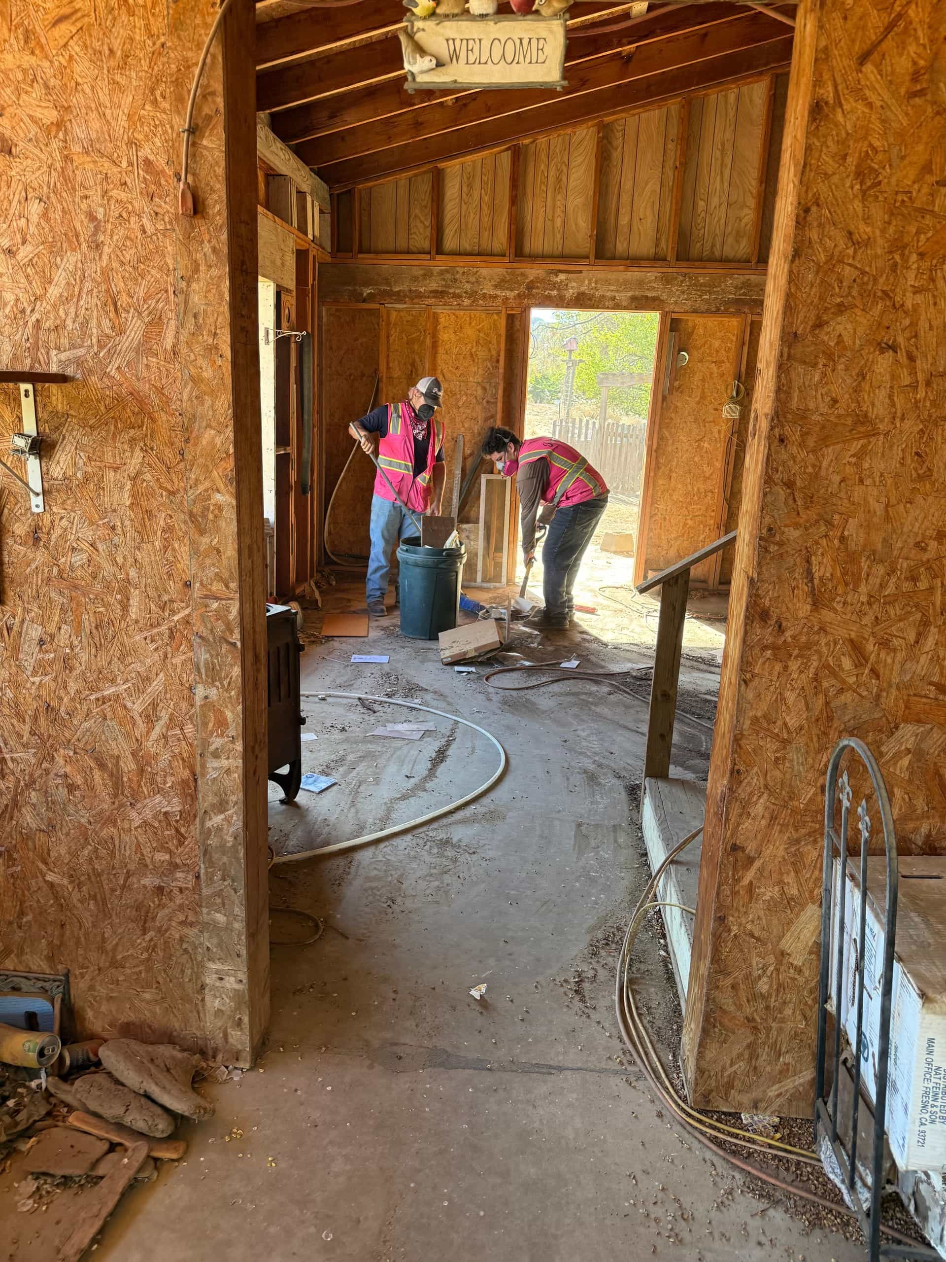 Two Papi's crew members sweeping out a barn after a cleanout in the foothills near Prather