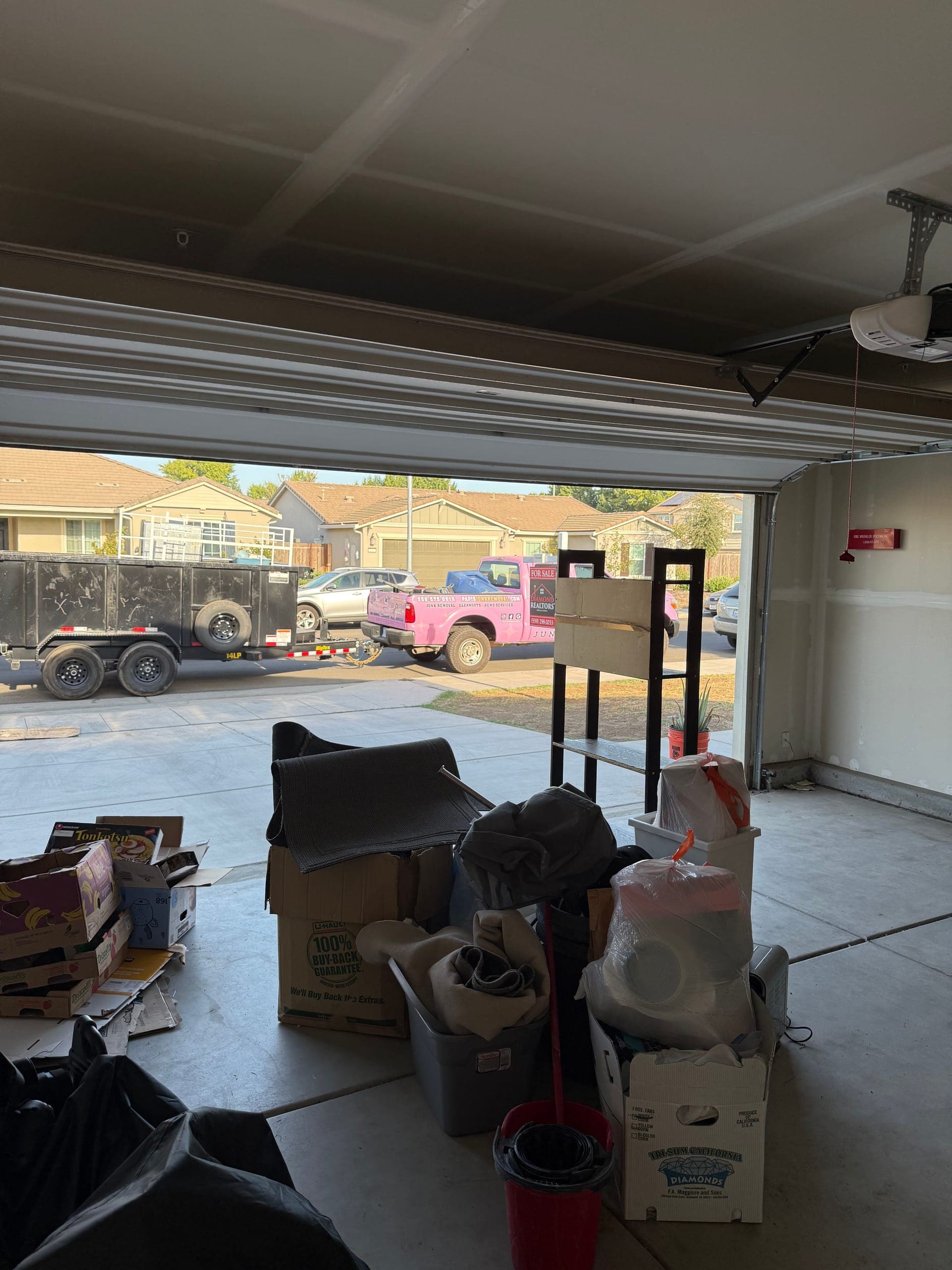 Garage full of boxes and bins near Clovis, Papi's pink truck and dump trailer waiting at the curb