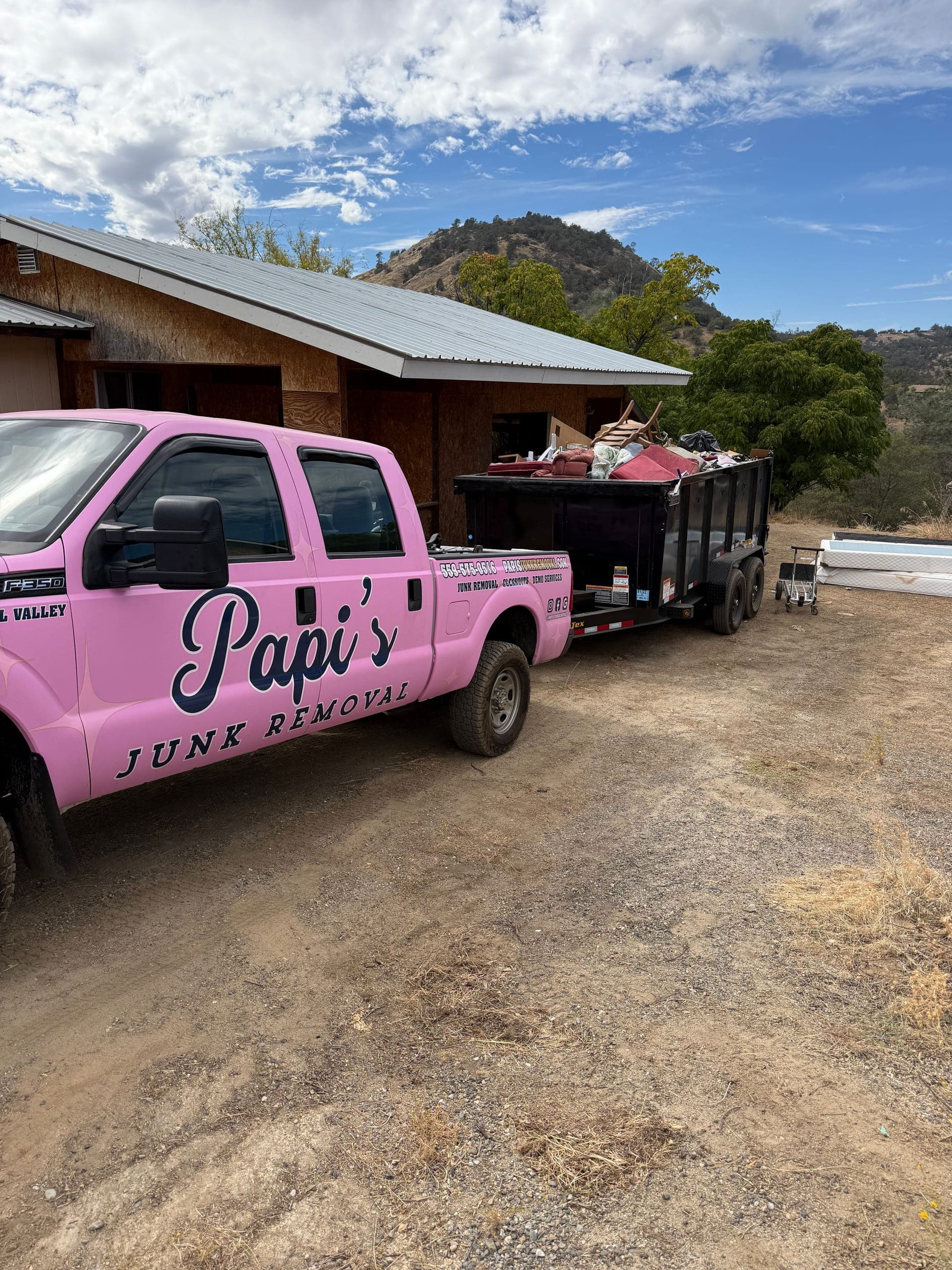 Papi's pink F-250 and a loaded dump trailer at a foothill property near Prather