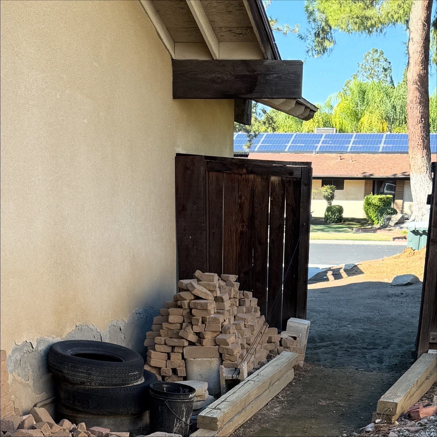 Side yard stacked with old bricks, tires and lumber waiting for pickup