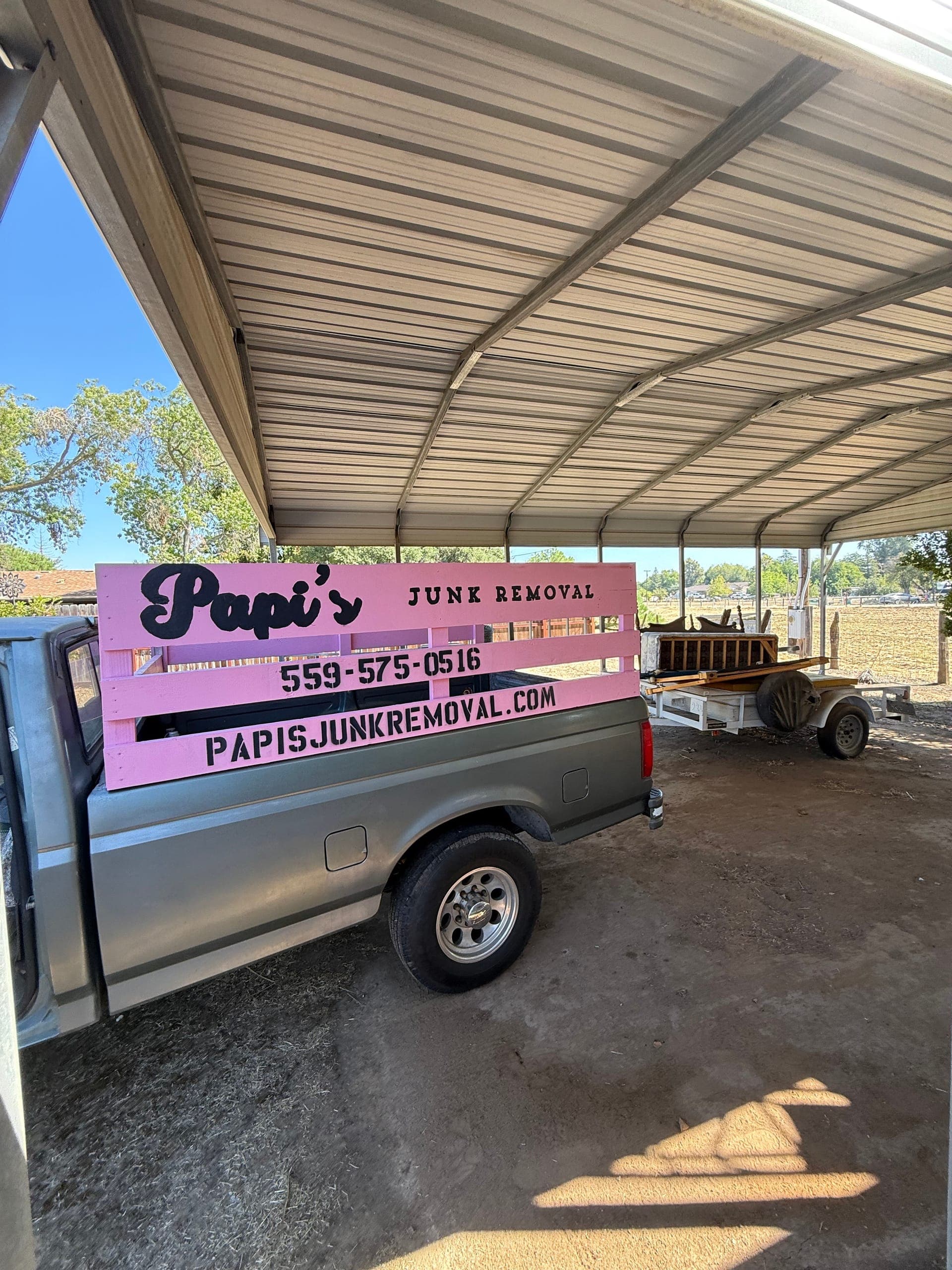 Papi's pink-rack truck and trailer parked under a metal carport