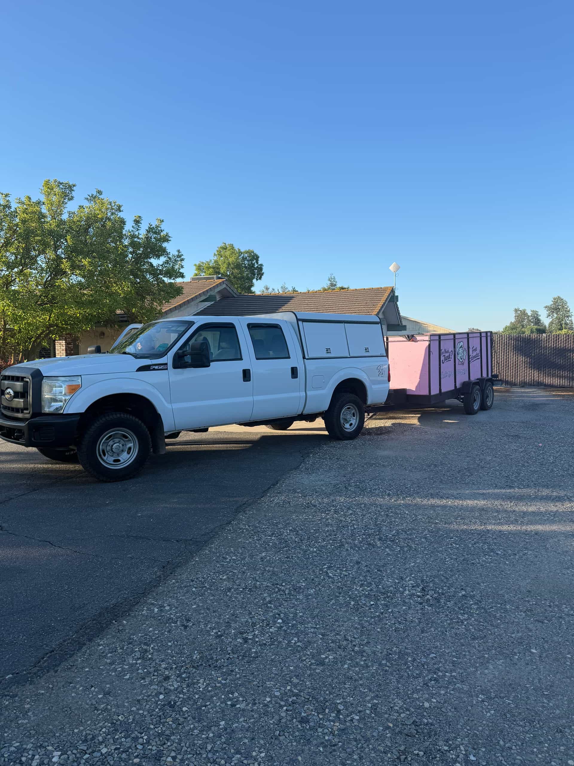Papi's white pickup towing the pink enclosed trailer, parked on gravel at sunrise