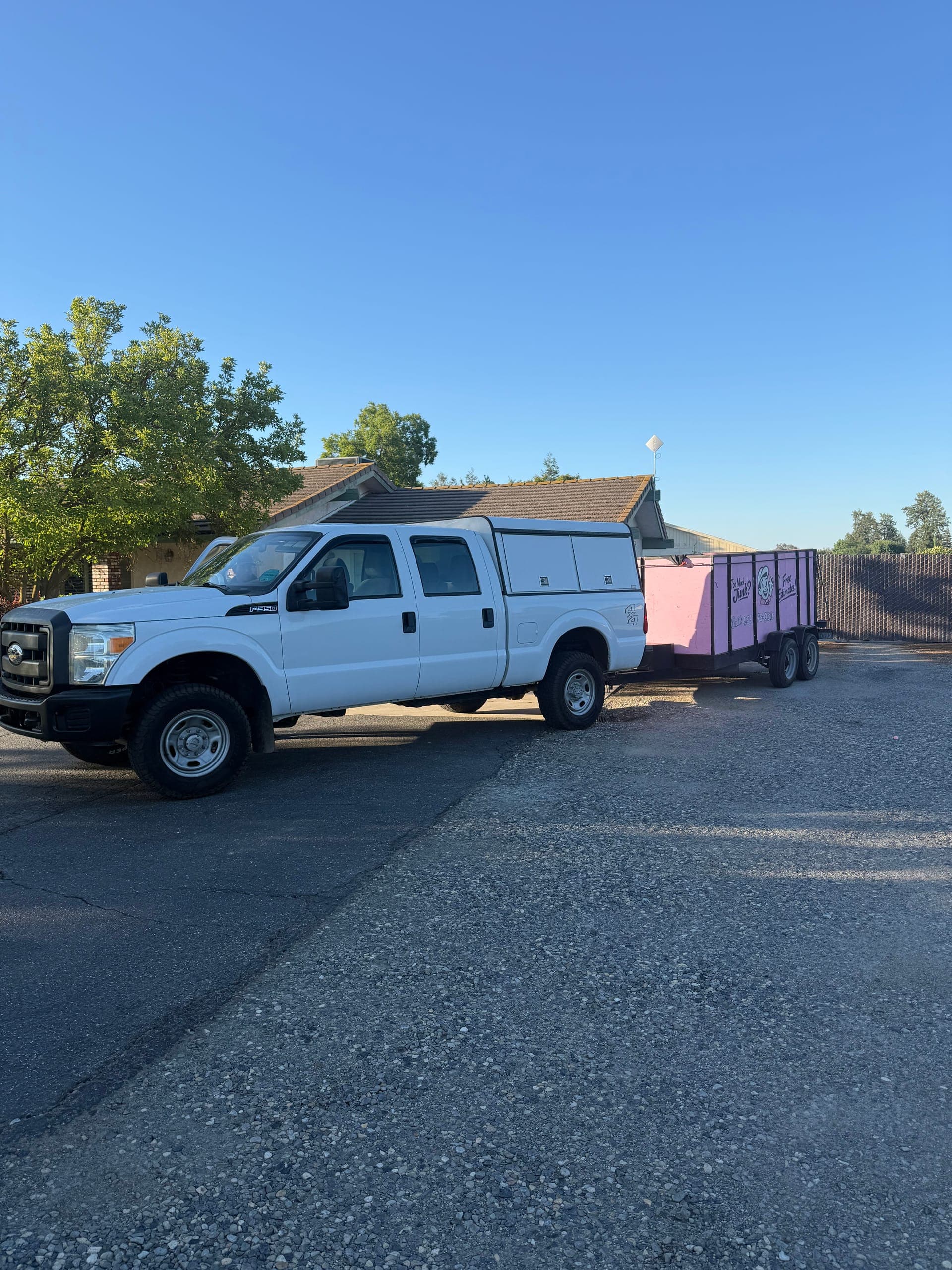 Papi's white pickup towing the pink enclosed trailer, parked on gravel at sunrise